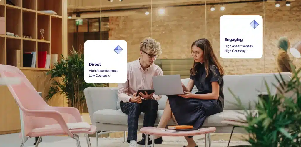 In a modern office setting, two people sit on a couch, focused on a laptop. Speech bubbles highlight their thoughts: "Direct: High Assertiveness, Low Courtesy" and "Engaging: High Assertiveness, High Courtesy." Their discussion emphasizes the importance of team dynamics.